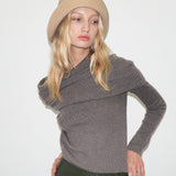 Woman wearing a gray sweater and beige beret against a white background