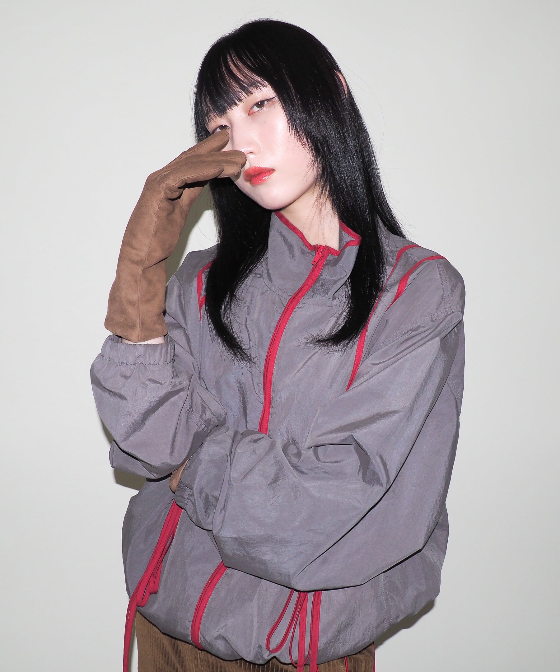 Person wearing a gray jacket with red accents against a plain background