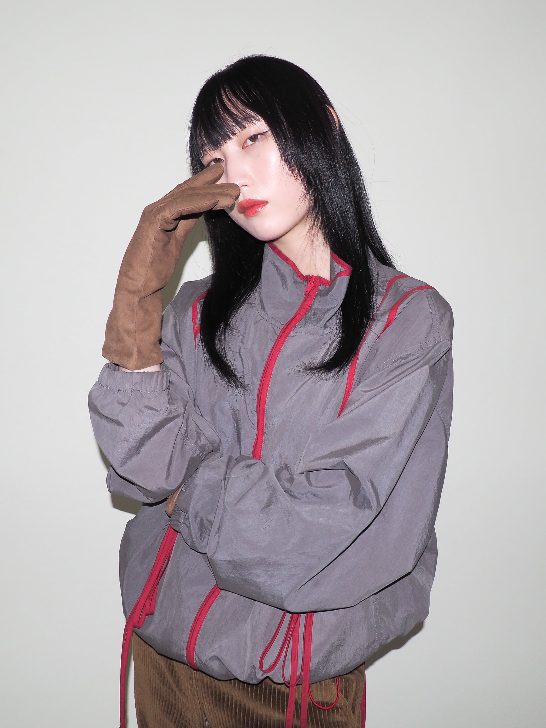 Person wearing a gray jacket with red accents against a plain background