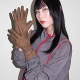 Person wearing a gray outfit with red accents and brown gloves against a white background