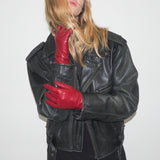 Person wearing a black leather jacket and red gloves on a white background