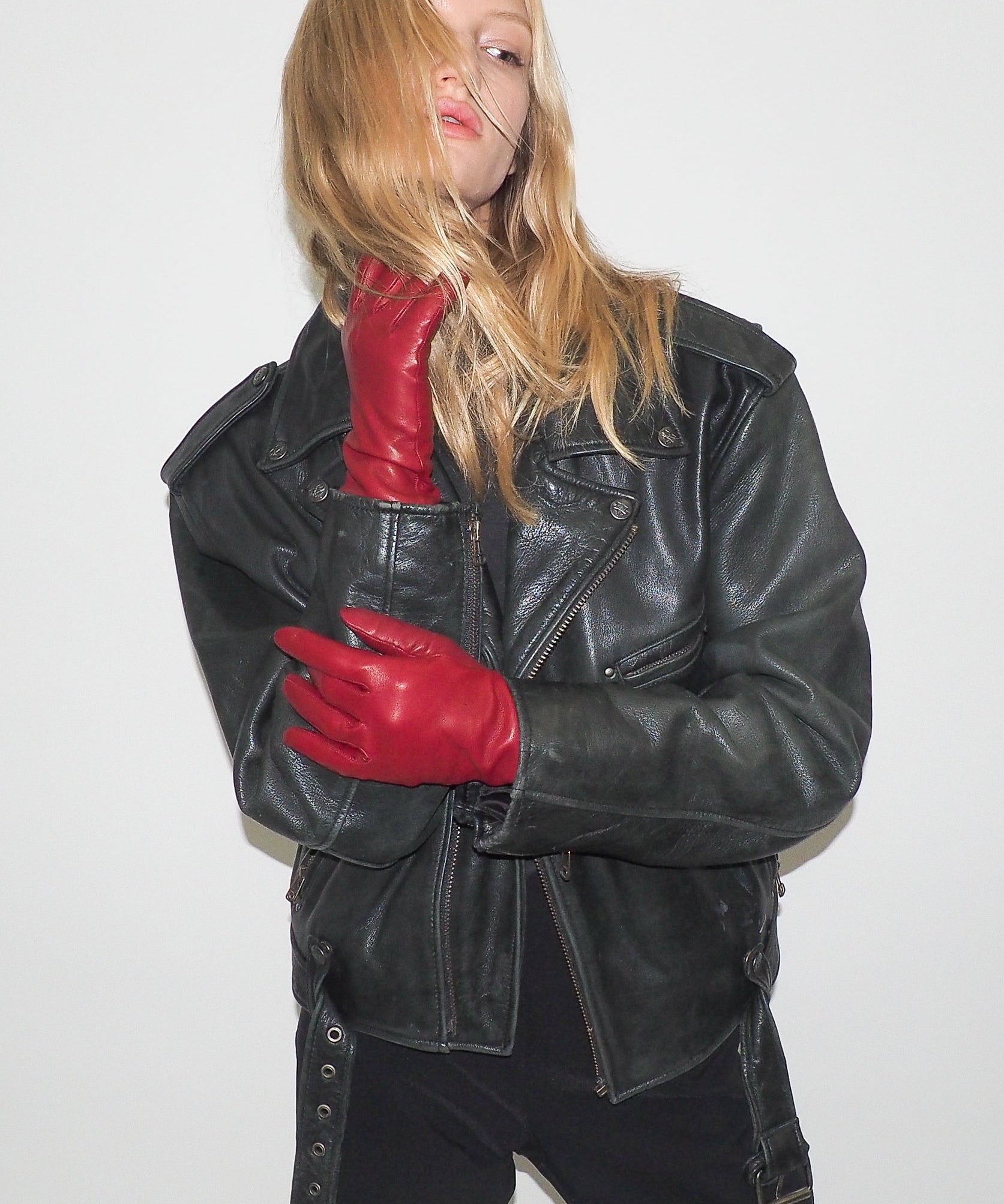Person wearing a black leather jacket and red gloves on a white background