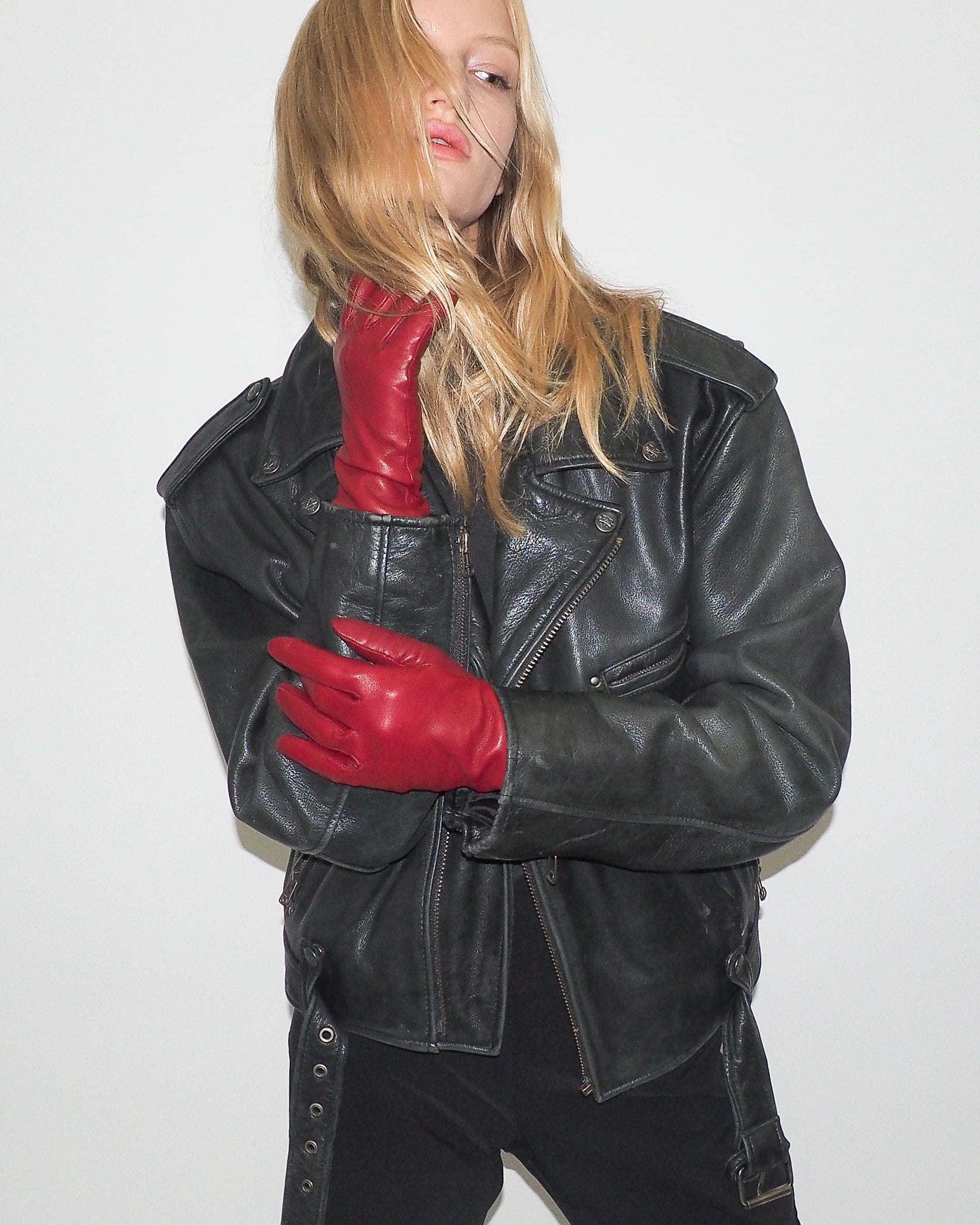 Person wearing a black leather jacket and red gloves on a white background