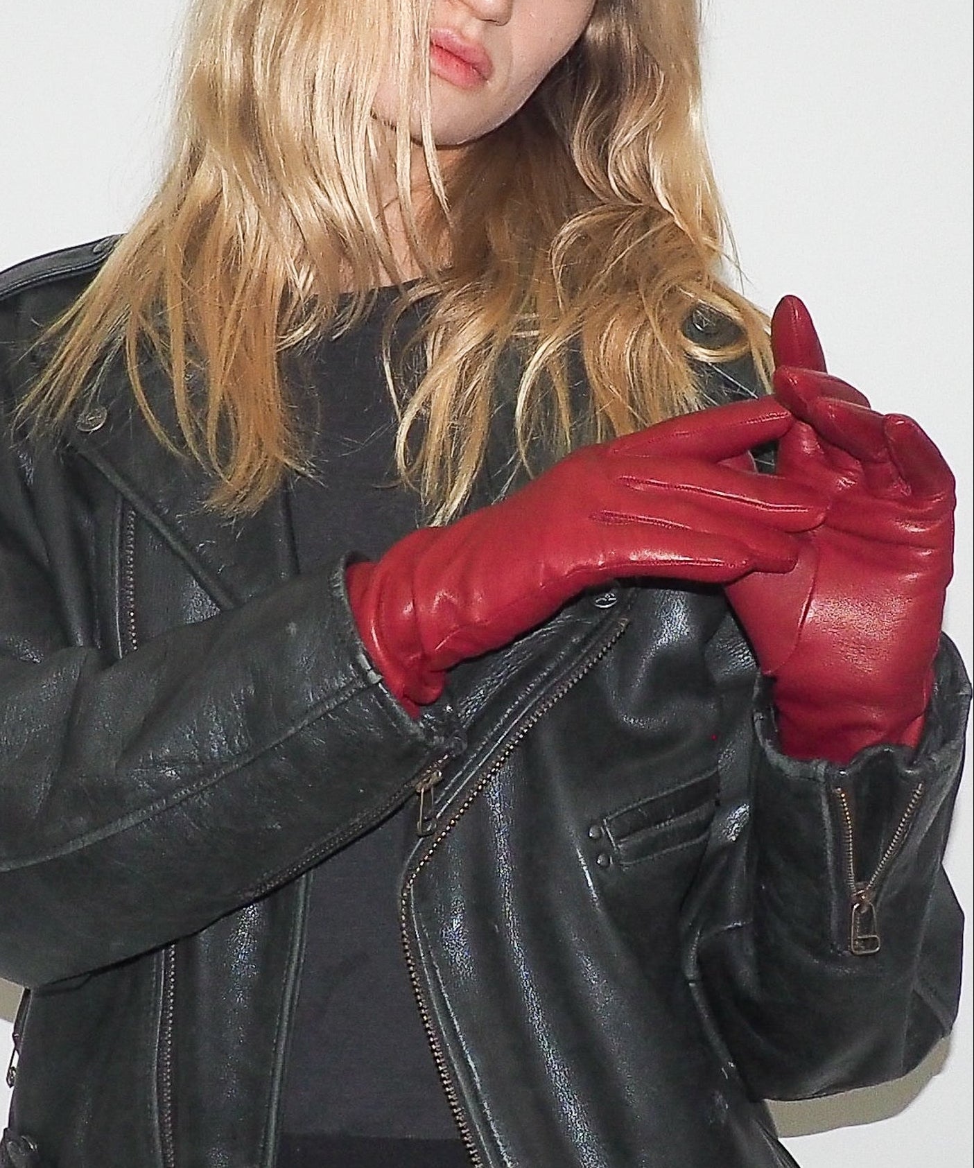 Person wearing a black leather jacket and red gloves on a white background
