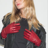 Woman wearing red leather gloves and a black jacket on a white background
