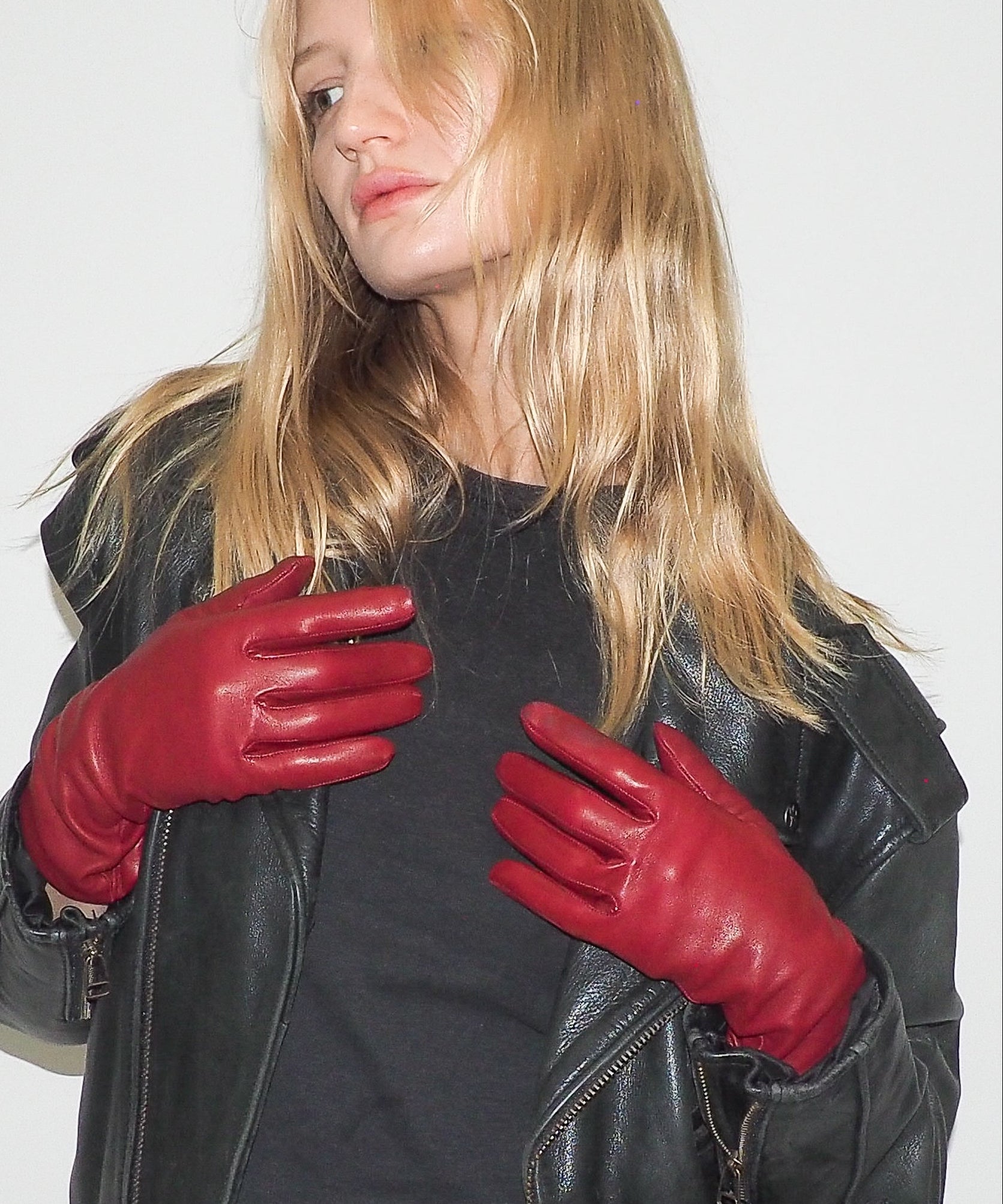 Woman wearing red leather gloves and a black jacket on a white background