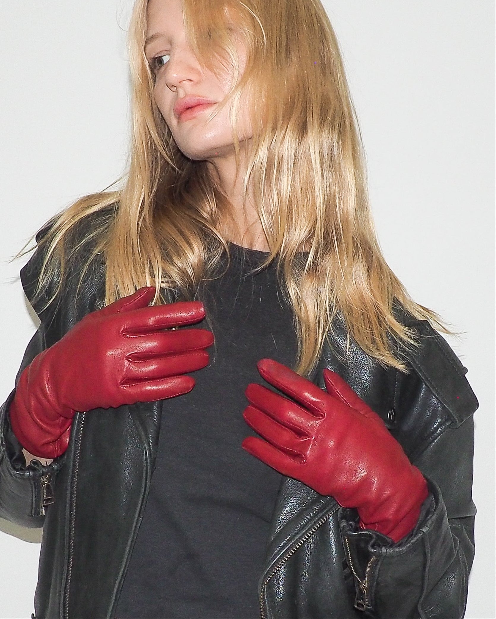 Woman wearing red leather gloves and a black jacket on a white background