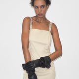 Woman wearing a beige dress and black gloves on a white background