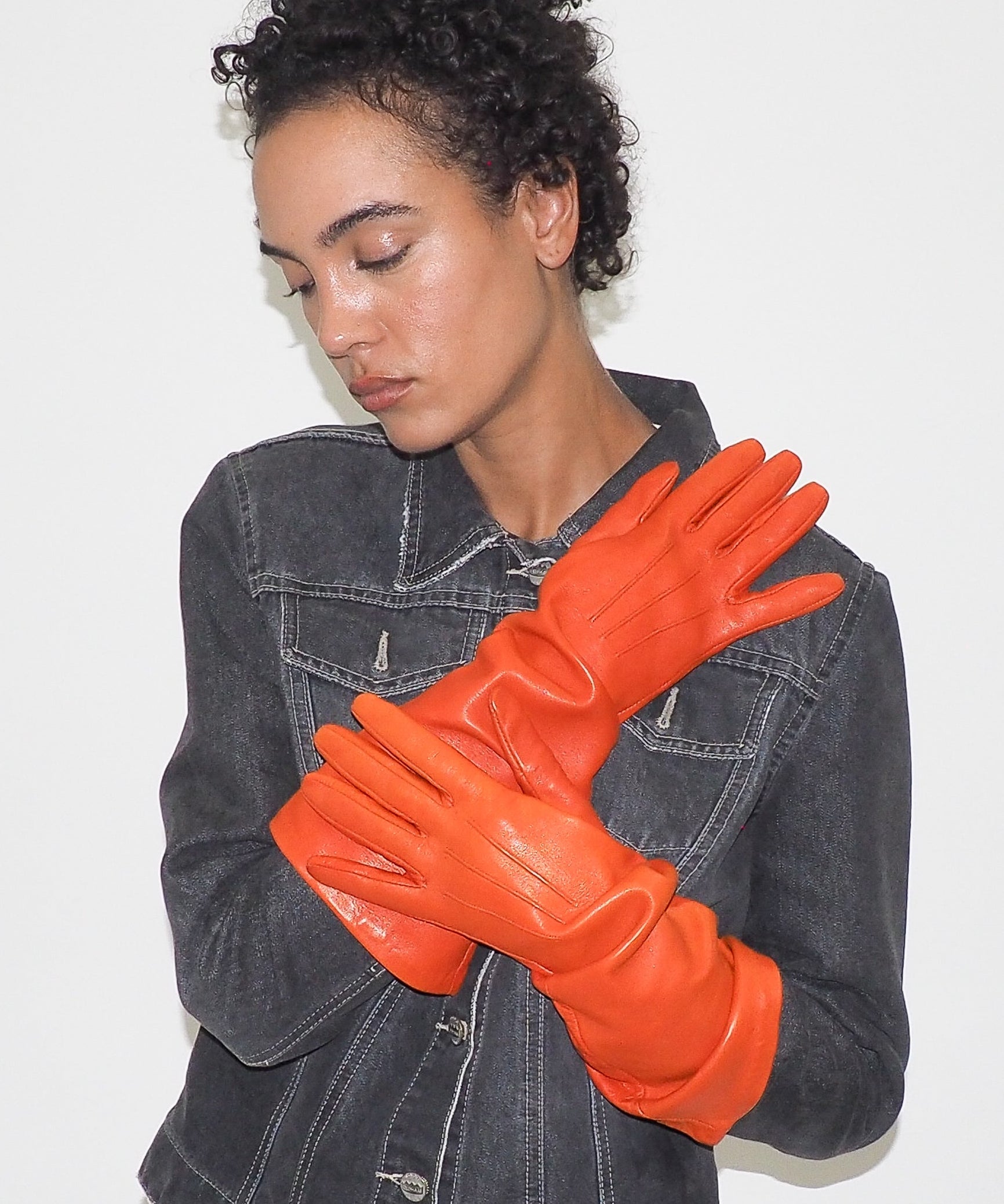 Person wearing orange gloves with a plain background