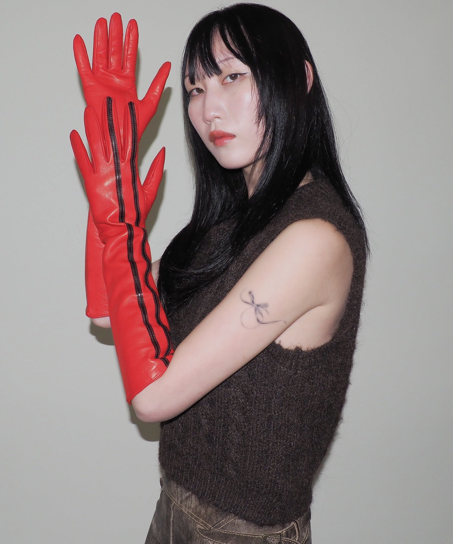 Person wearing red gloves with black stripes against a plain background