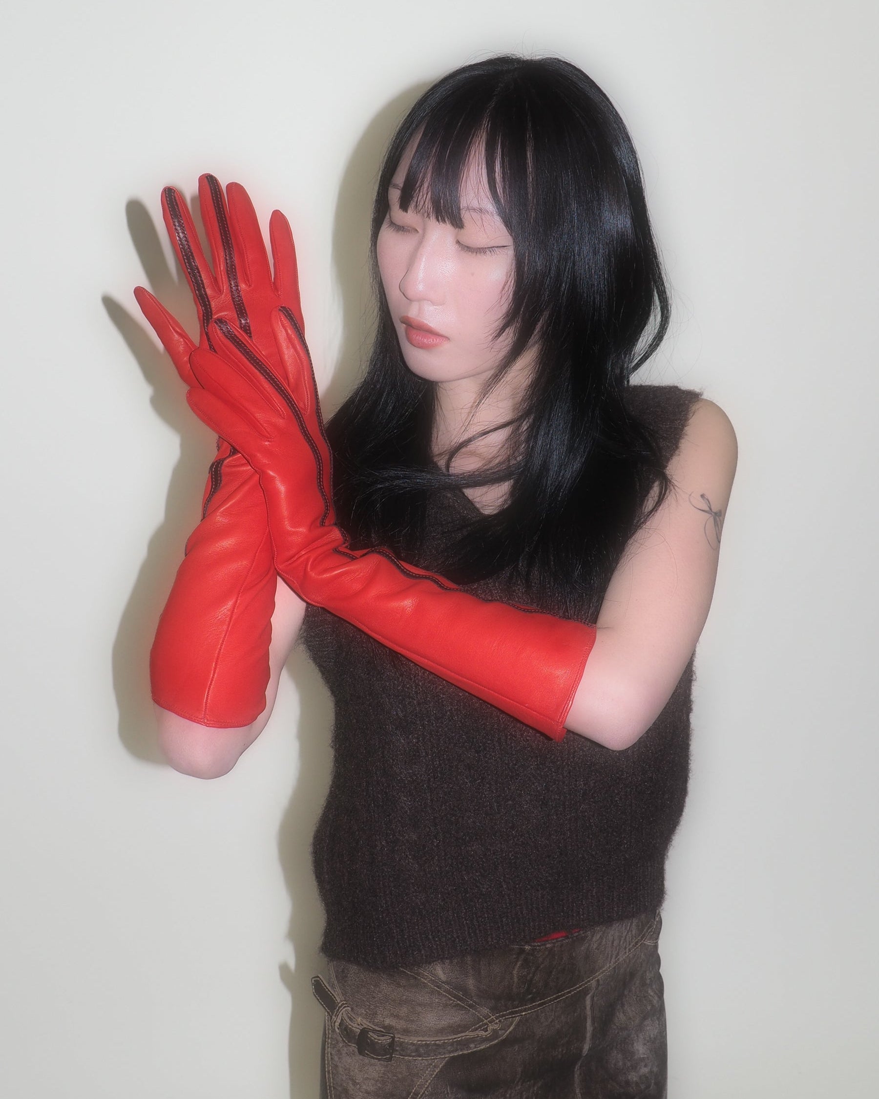 Person wearing red gloves against a plain background