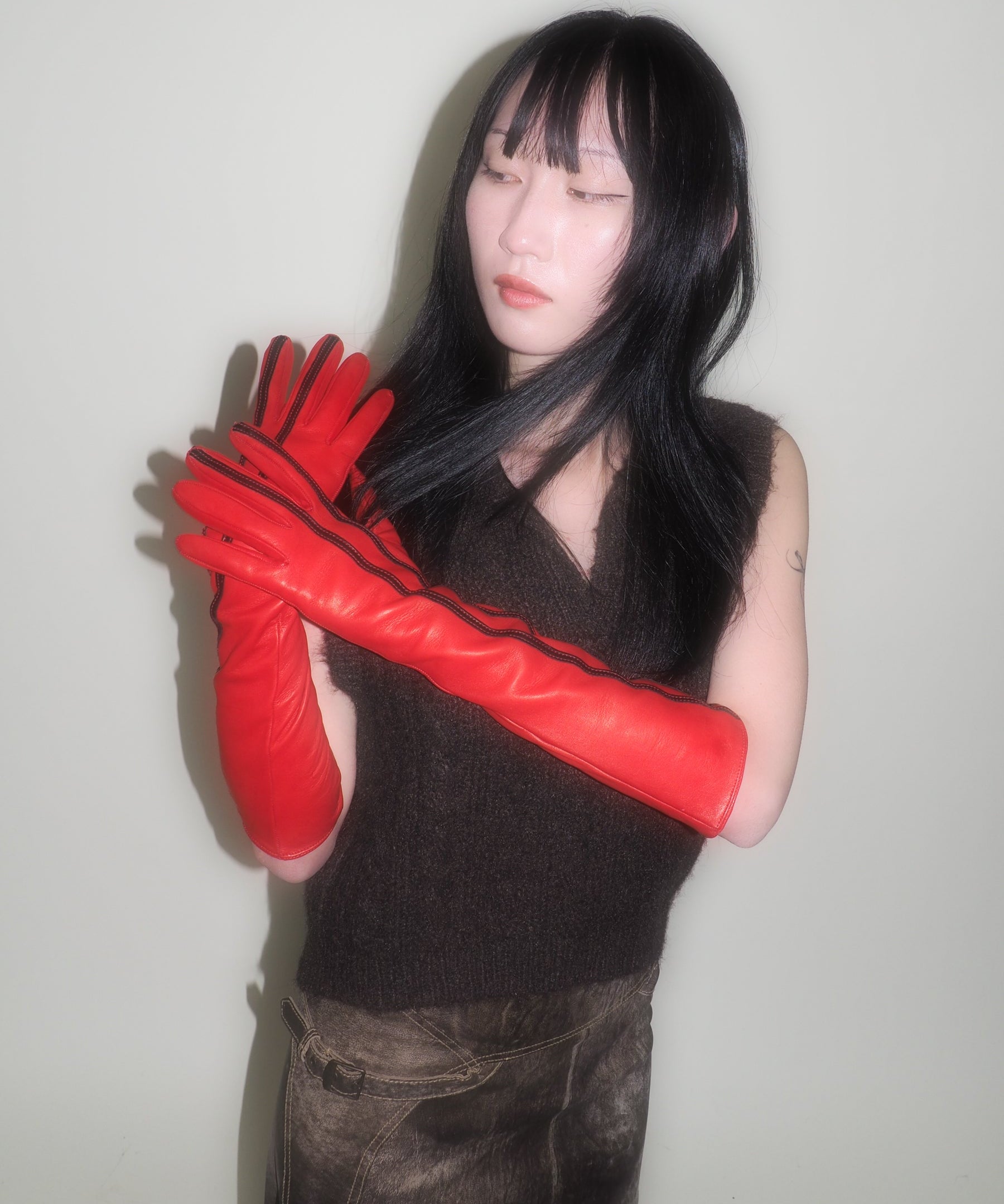 Person wearing red gloves with a plain background