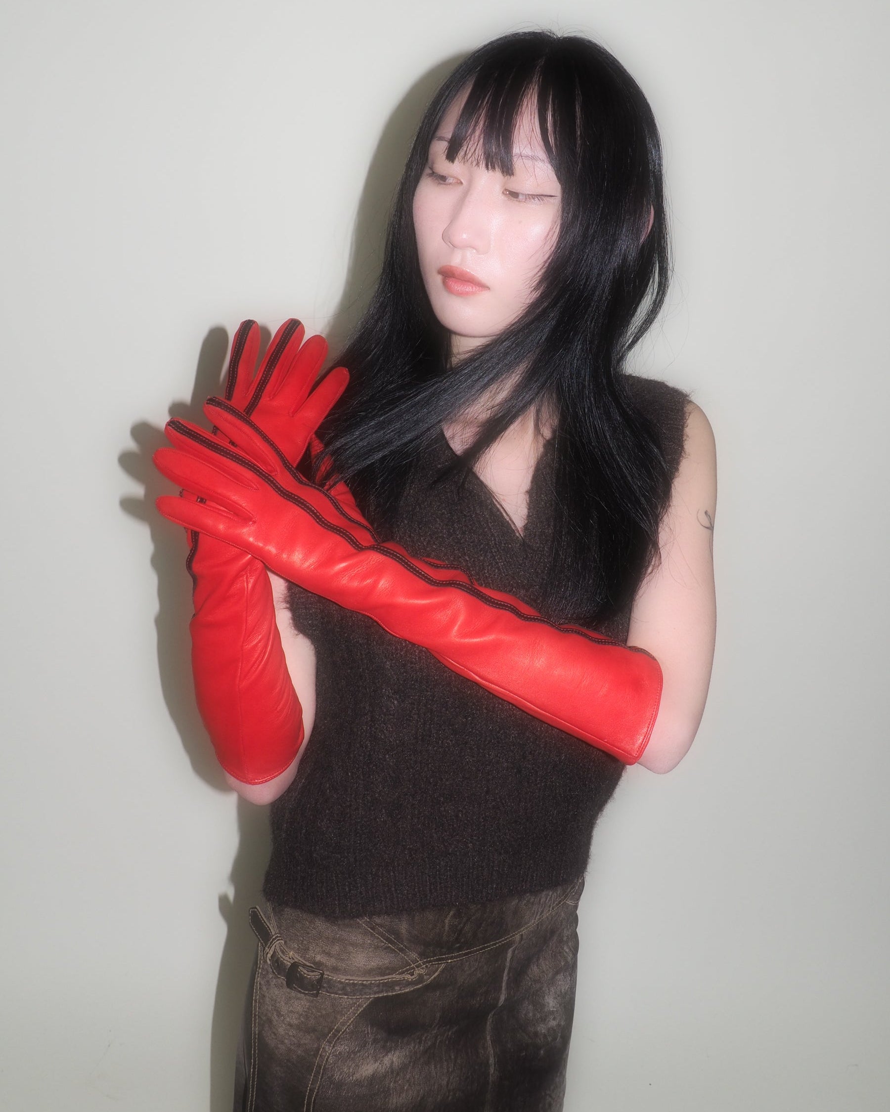 Person wearing red gloves with a plain background