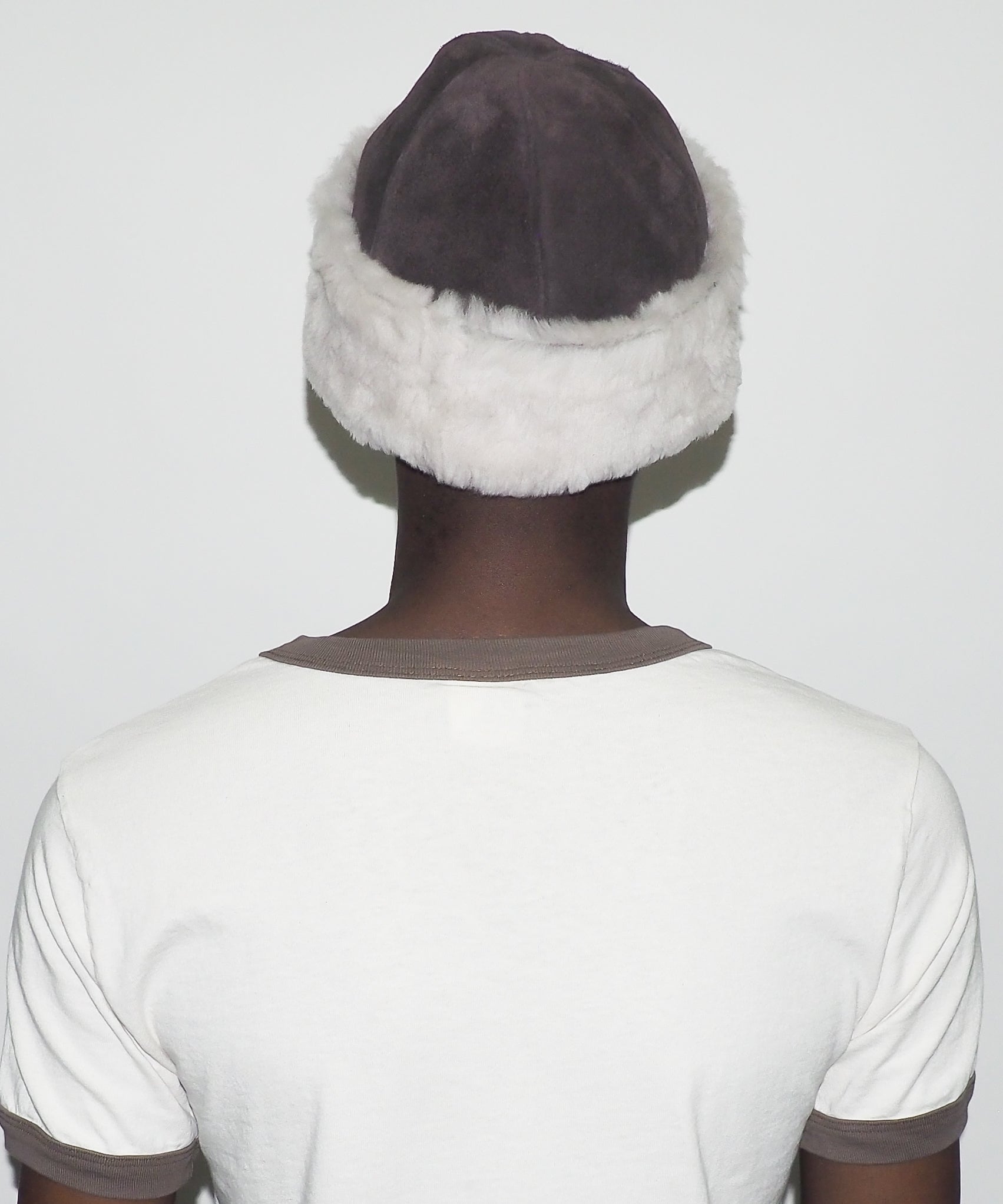 Person wearing a white headband with gray fur trim on a plain background