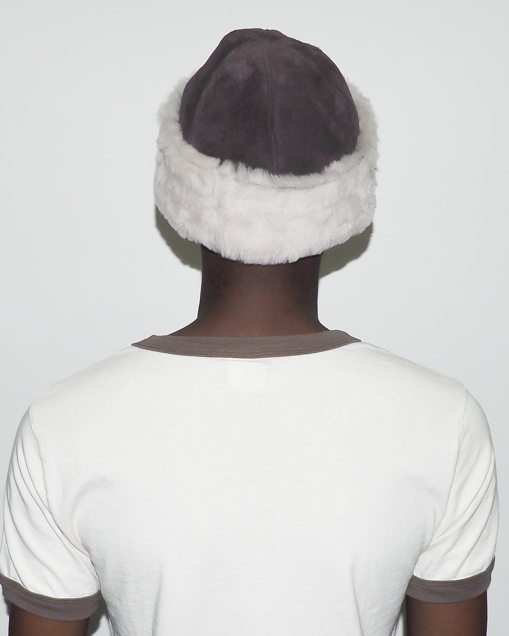 Person wearing a white headband with gray fur trim on a plain background