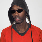 Person wearing a black hood and red sweater with sunglasses on a white background