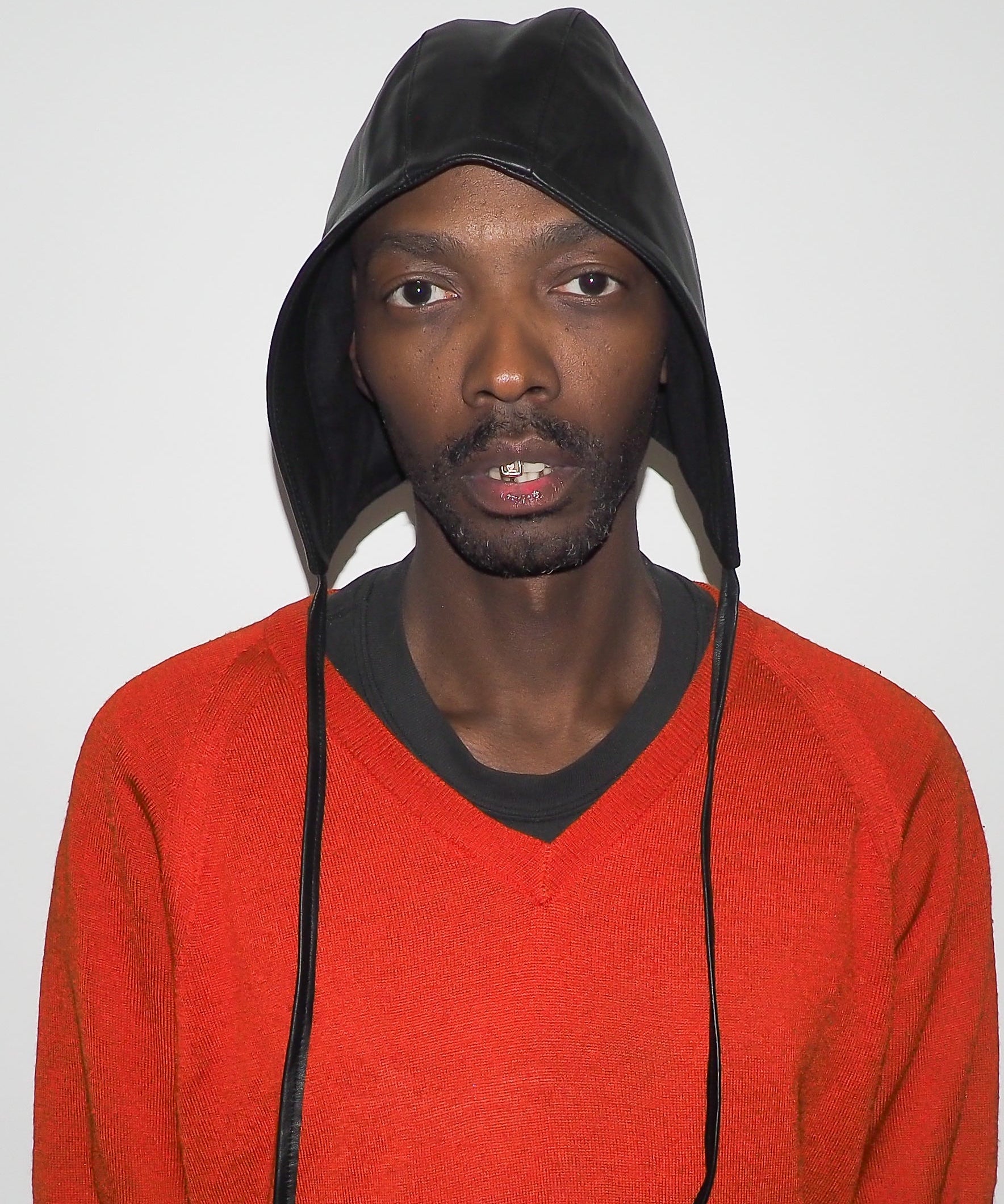 Person wearing a red sweater and black hooded cap against a plain background