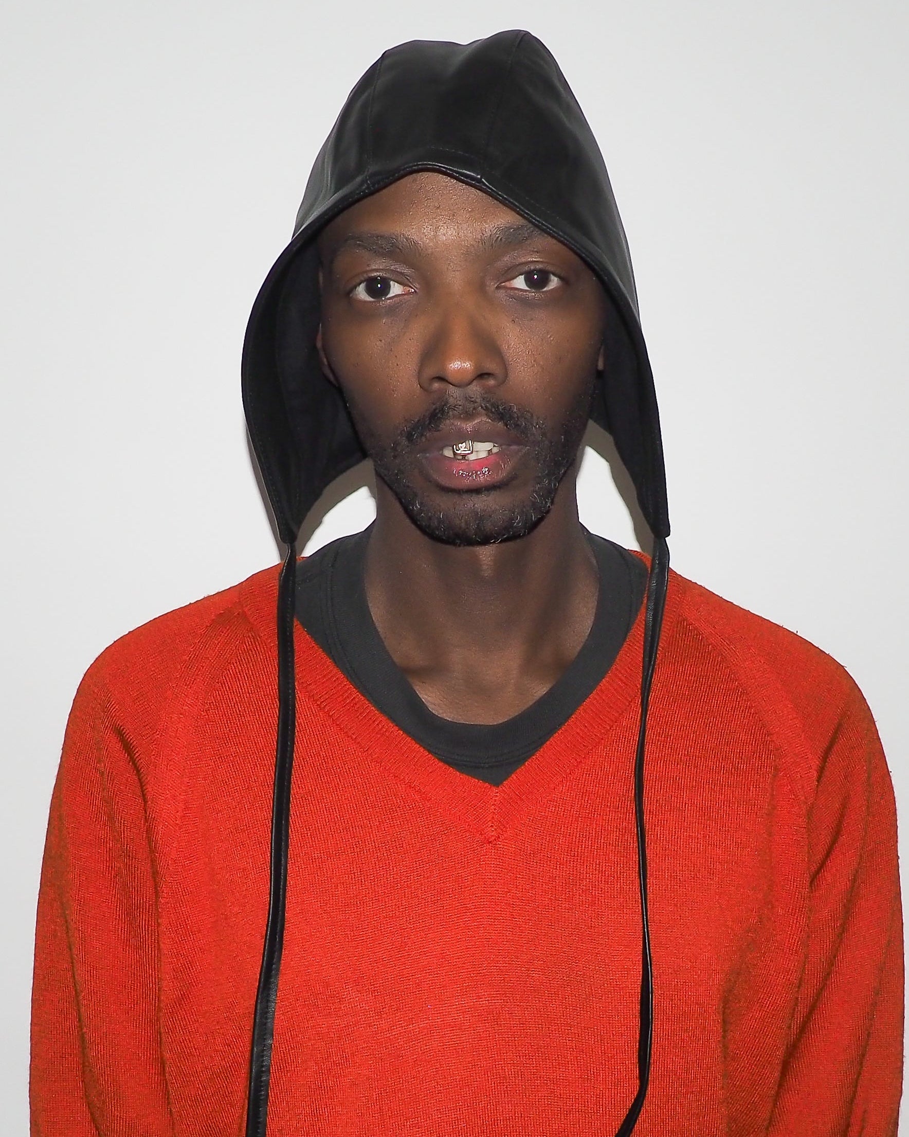 Person wearing a red sweater and black hooded cap against a plain background