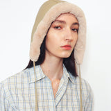 A model wearing a beige and cream plaid button-up shirt with a matching beige knit hood featuring faux-fur trim, set against a plain white background.