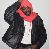 Person wearing a black leather jacket, white shirt, and red hoodie against a plain background