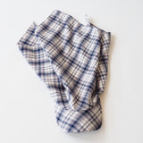 A folded plaid fabric scarf in a cream, white, and navy blue checkered pattern, photographed on a clean white background.