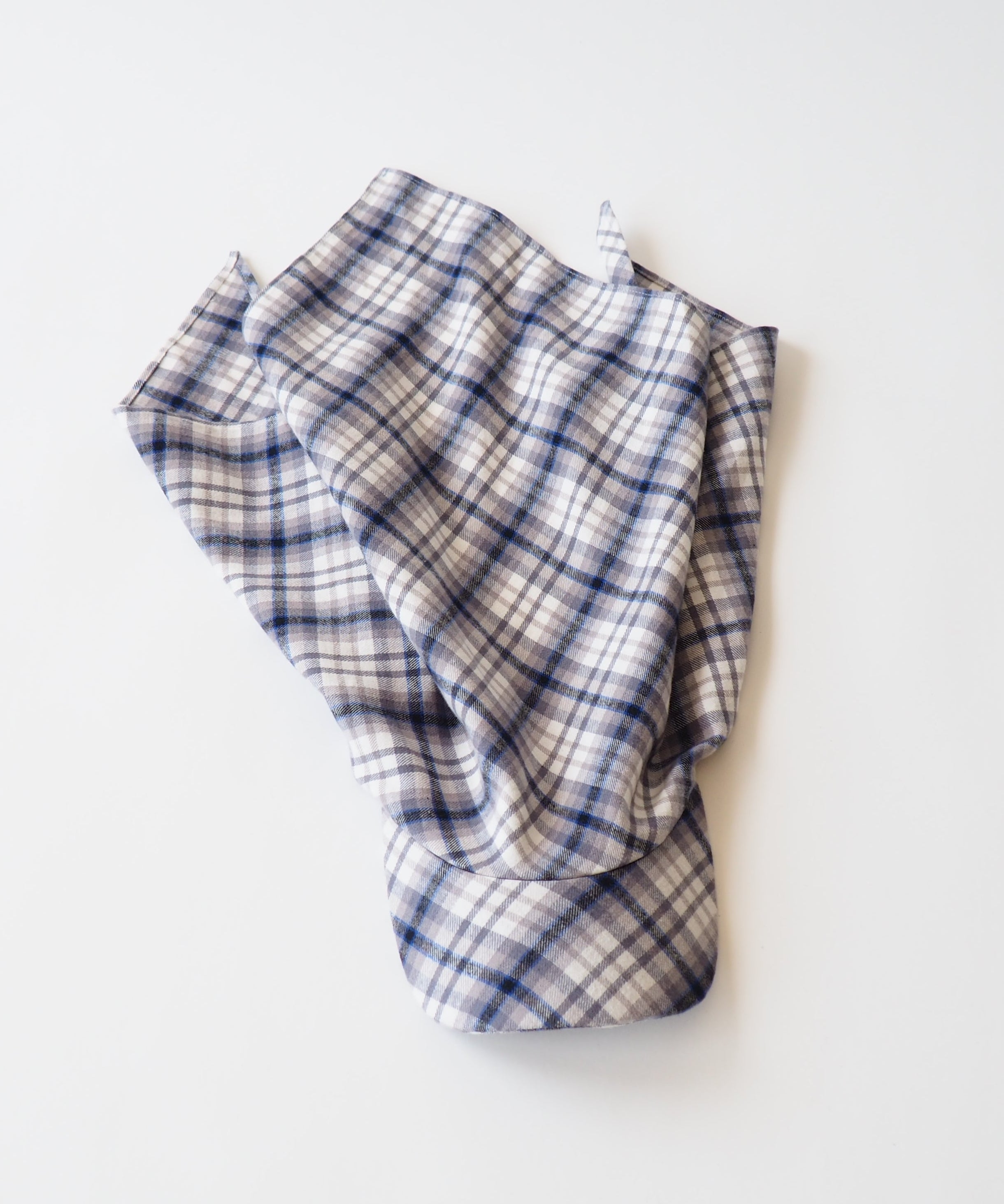 A folded plaid fabric scarf in a cream, white, and navy blue checkered pattern, photographed on a clean white background.
