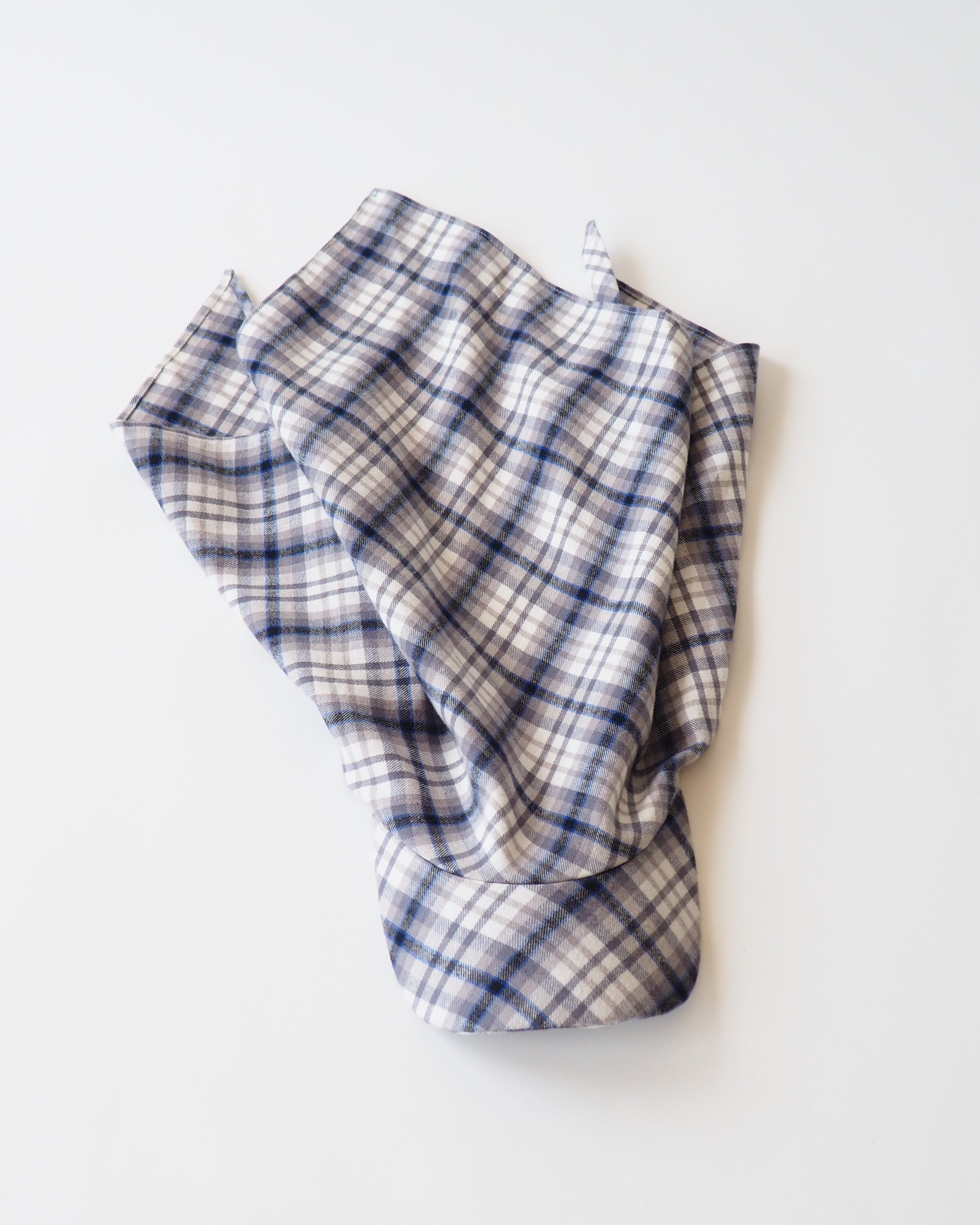 A folded plaid fabric scarf in a cream, white, and navy blue checkered pattern, photographed on a clean white background.