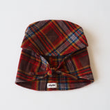 A plaid fabric hat with a tie closure at the front, featuring a red, brown, and blue tartan pattern, laid flat on a white background. A small white tag with the brand name 'clyde' is visible near the bottom.